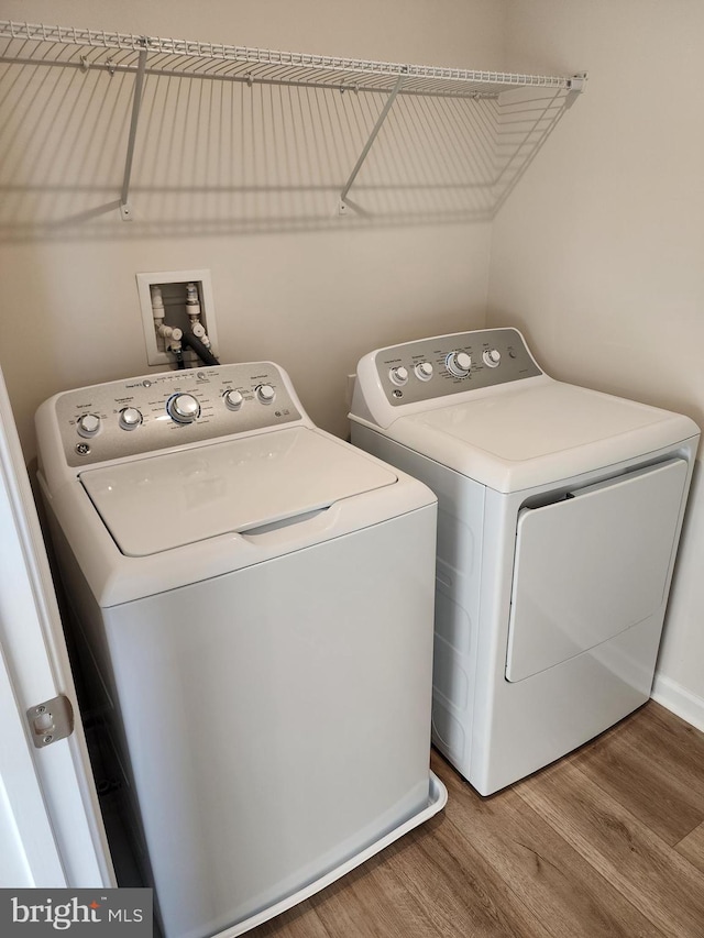 laundry area with wood finished floors, laundry area, and separate washer and dryer