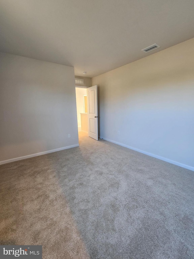 empty room with carpet, visible vents, and baseboards