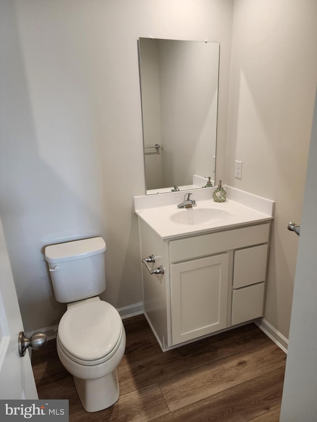 bathroom featuring baseboards, vanity, toilet, and wood finished floors