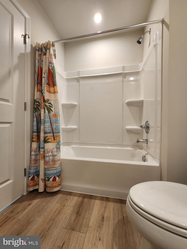 bathroom with shower / bath combination with curtain, wood finished floors, and toilet