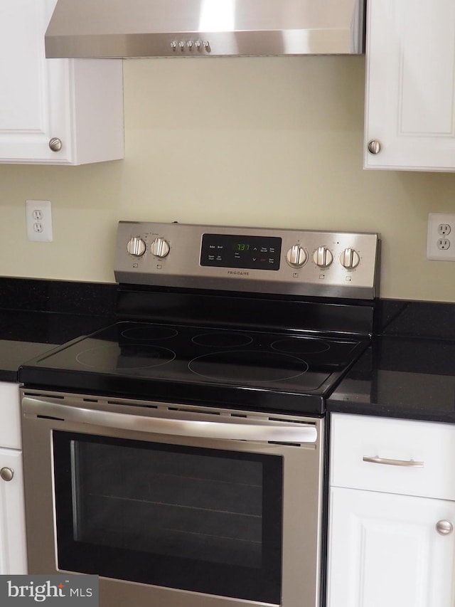 5711 Crownleigh Ct, Burke, VA 22015 - kitchen view of stainless steel electric stove, dark countertops, white cabinets, and wall chimney range hood