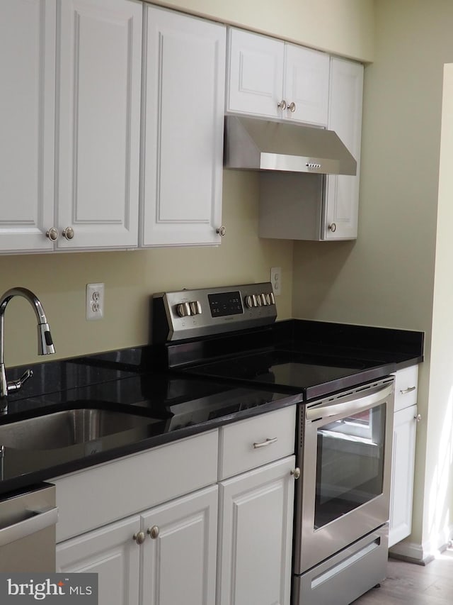 5711 Crownleigh Ct, Burke, VA 22015 - kitchen with under cabinet range hood, stainless steel range with electric cooktop, white cabinetry, and dark countertops