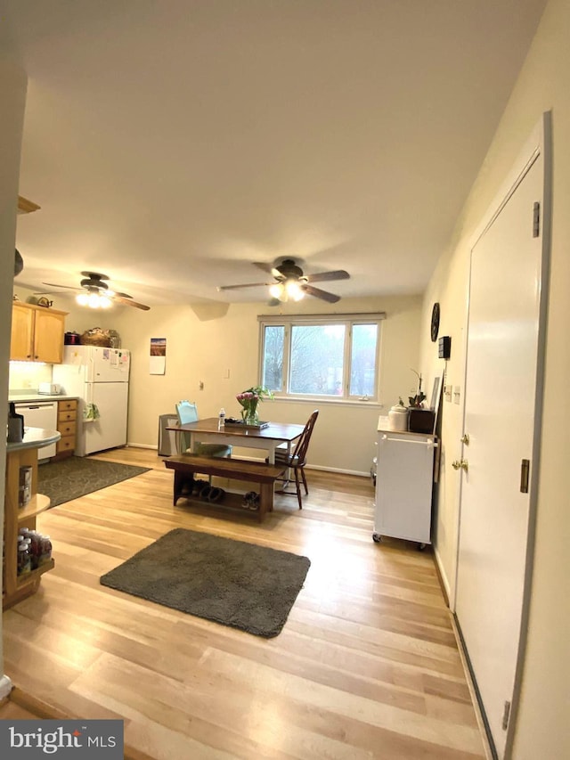 dining space with light wood-style flooring, baseboards, and a ceiling fan