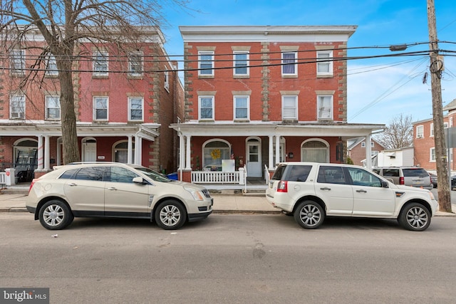 multi unit property with brick siding and a porch