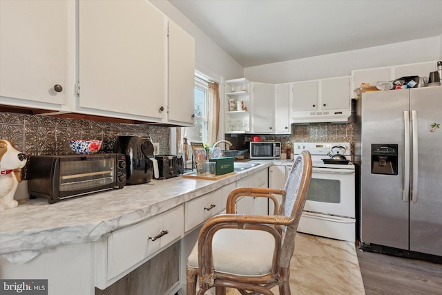 kitchen with under cabinet range hood, tasteful backsplash, white cabinetry, stainless steel appliances, and light countertops