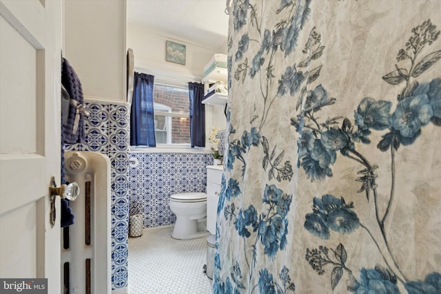 bathroom with radiator heating unit, crown molding, tile walls, toilet, and tile patterned floors