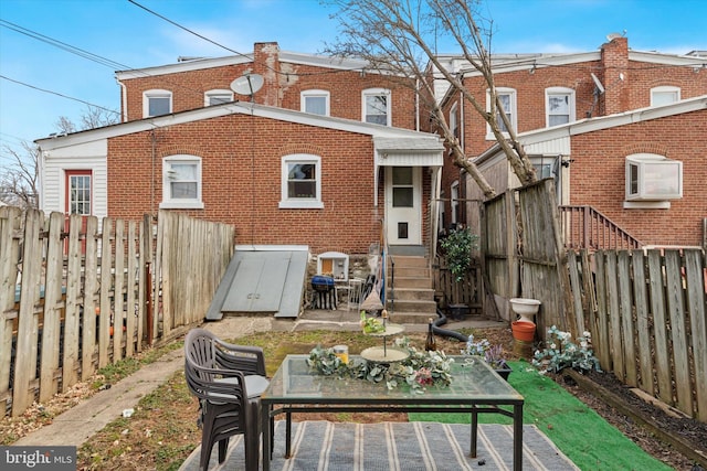 back of house featuring entry steps, outdoor dining area, a fenced backyard, and brick siding