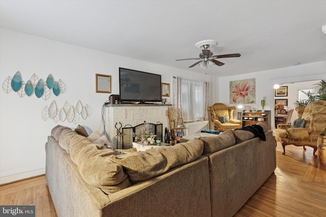 living area with ceiling fan, wood finished floors, and a fireplace