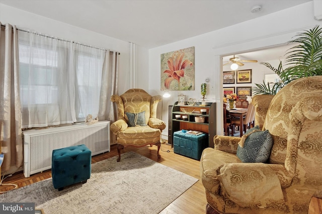 sitting room featuring radiator, wood finished floors, and a ceiling fan