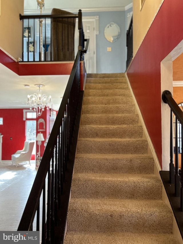 stairs featuring crown molding and an inviting chandelier