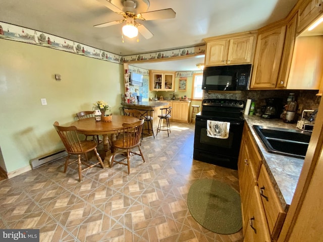 kitchen featuring a ceiling fan, baseboard heating, light brown cabinetry, black appliances, and a sink