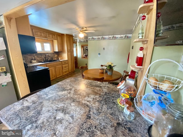 kitchen featuring decorative backsplash, a ceiling fan, brown cabinetry, a sink, and black / electric stove