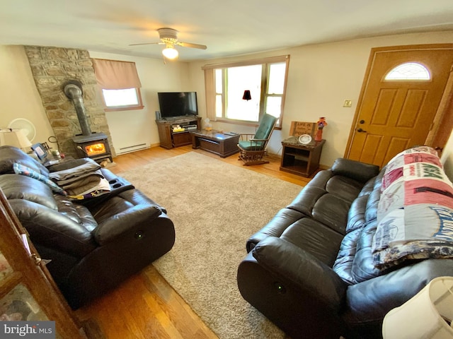 living area with a healthy amount of sunlight, baseboard heating, and wood finished floors