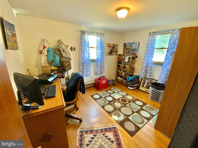 office area with plenty of natural light, a baseboard heating unit, and wood finished floors