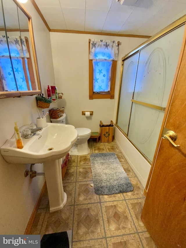 bathroom featuring enclosed tub / shower combo, crown molding, and toilet