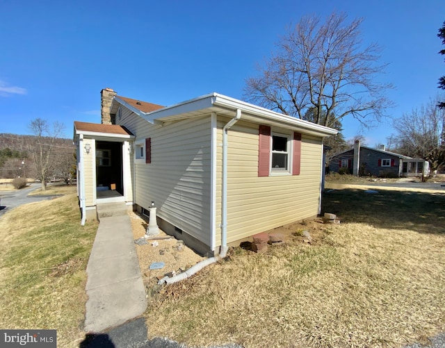 view of side of home with a lawn and a chimney