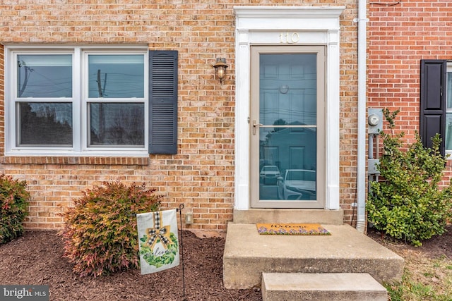 view of exterior entry featuring brick siding