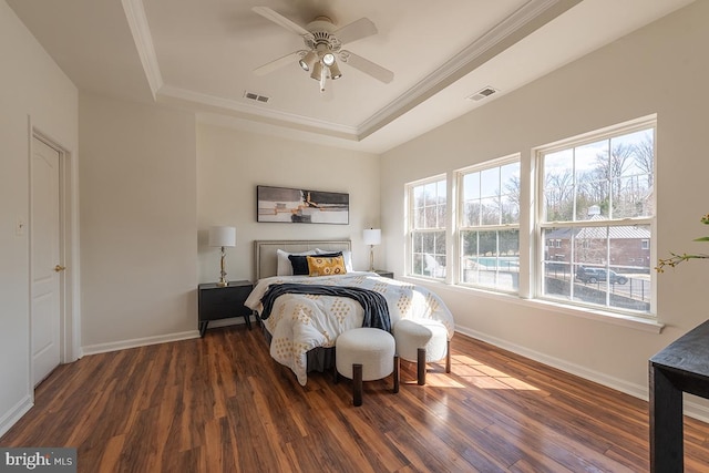 bedroom with ornamental molding, a raised ceiling, visible vents, and wood finished floors