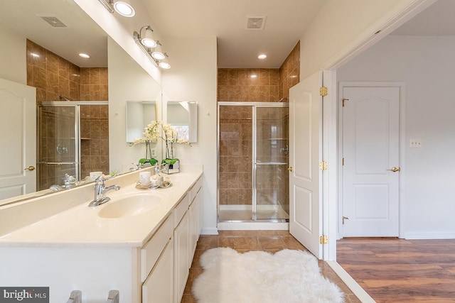 bathroom with a stall shower, visible vents, and vanity