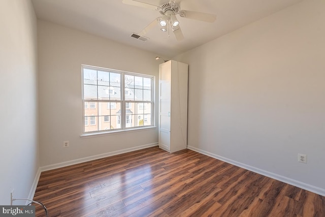 unfurnished room with dark wood-style floors, a ceiling fan, visible vents, and baseboards