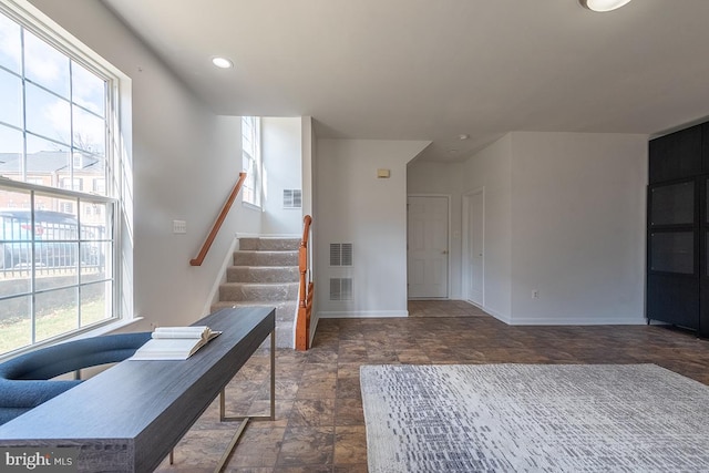 interior space featuring stone finish flooring, a healthy amount of sunlight, visible vents, and baseboards