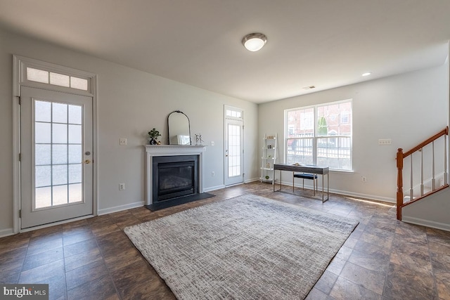 foyer entrance featuring a glass covered fireplace, visible vents, stairway, and baseboards