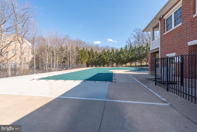 community pool with a patio area and fence