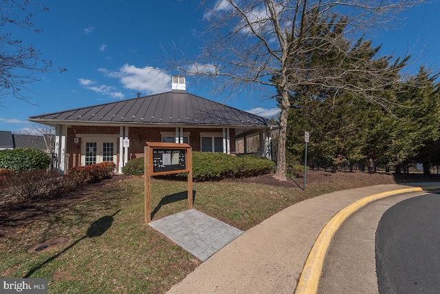 view of front of home with metal roof, brick siding, french doors, a standing seam roof, and a front yard