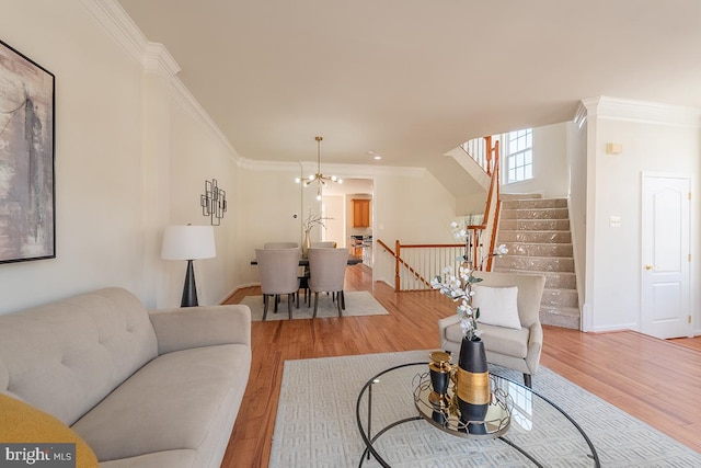 living room with ornamental molding, light wood-style floors, and a notable chandelier