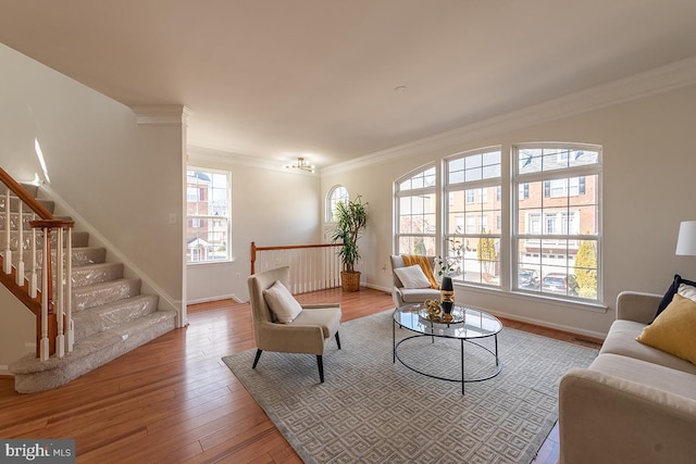 living room featuring baseboards, wood finished floors, stairs, and crown molding