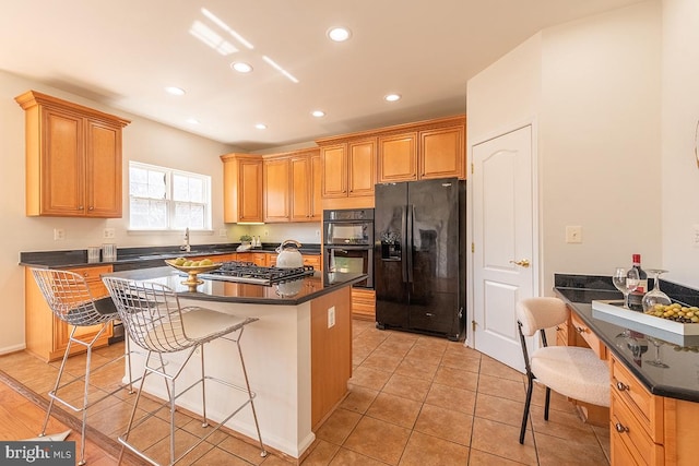 kitchen featuring dark countertops, black appliances, a breakfast bar area, and recessed lighting