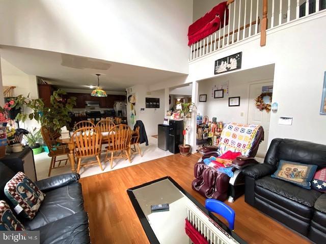 living area with a towering ceiling and wood finished floors