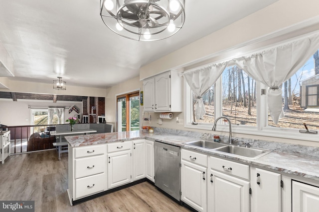 kitchen featuring dishwasher, light wood-style flooring, a peninsula, white cabinets, and a sink