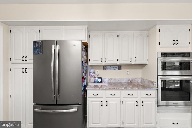 kitchen with white cabinetry, stainless steel appliances, and light stone countertops