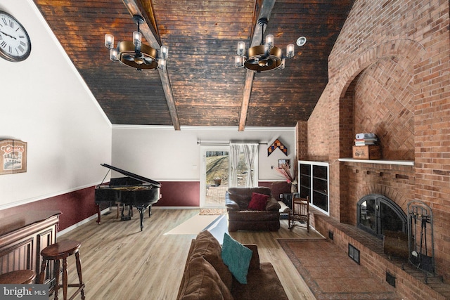 unfurnished living room featuring a chandelier, beam ceiling, a fireplace, wood finished floors, and high vaulted ceiling