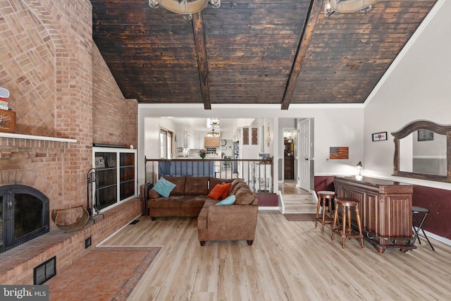 living area with beam ceiling, high vaulted ceiling, ornamental molding, wood finished floors, and a fireplace