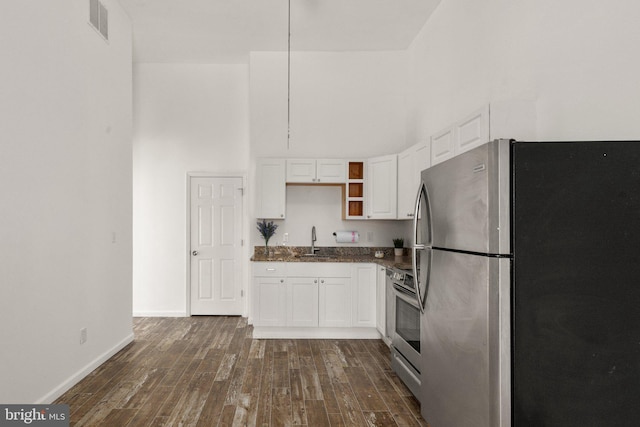 kitchen with dark wood-style floors, a high ceiling, a sink, stainless steel appliances, and white cabinetry