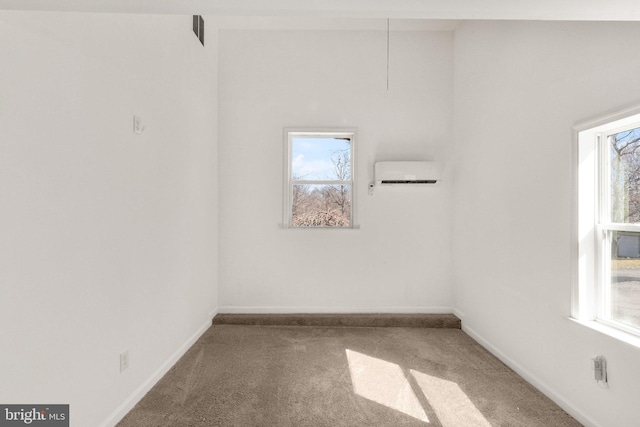 carpeted empty room with a wall unit AC, plenty of natural light, and baseboards