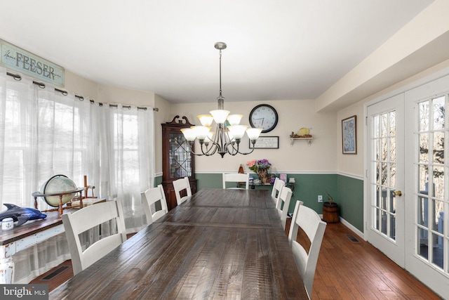 dining area with a notable chandelier, visible vents, french doors, and hardwood / wood-style floors