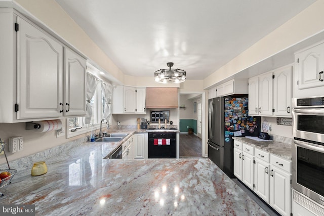 kitchen with white cabinetry, light stone countertops, stainless steel appliances, and a sink