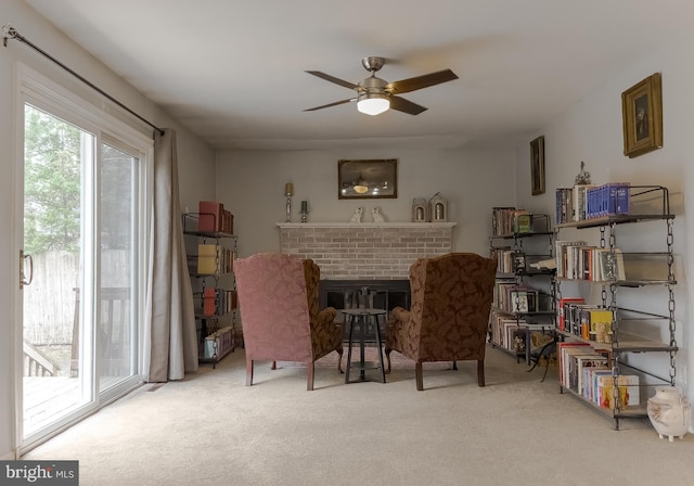 sitting room featuring ceiling fan, a fireplace, and carpet