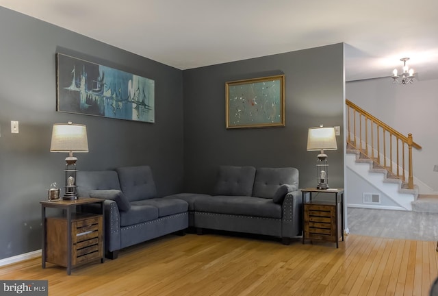 living area with visible vents, wood finished floors, baseboards, a chandelier, and stairs