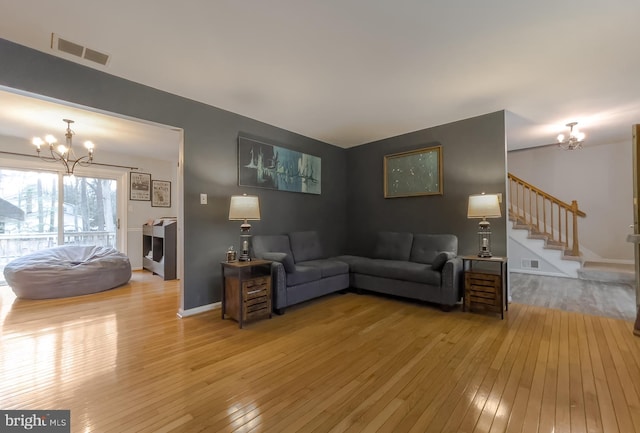 living area with visible vents, wood-type flooring, a notable chandelier, and stairs