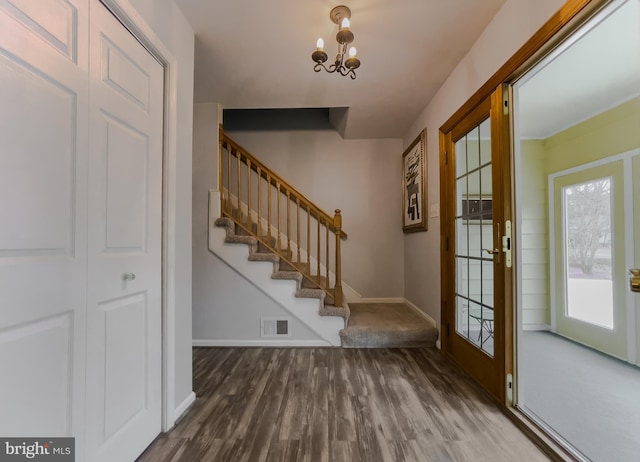 entryway with visible vents, a notable chandelier, wood finished floors, stairway, and baseboards