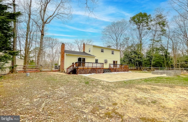 rear view of property featuring a patio, fence, a chimney, and a wooden deck