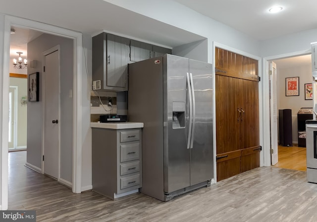 kitchen featuring gray cabinets, light wood-style flooring, stainless steel fridge with ice dispenser, and light countertops