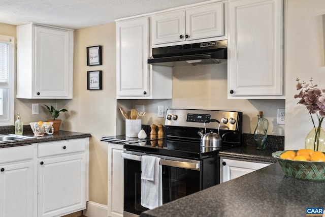 kitchen with dark countertops, stainless steel electric range, white cabinets, and under cabinet range hood