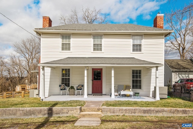 view of front of property featuring a chimney, fence, a porch, and a front yard