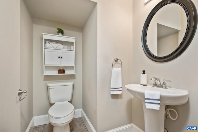 half bath with tile patterned flooring, toilet, and baseboards