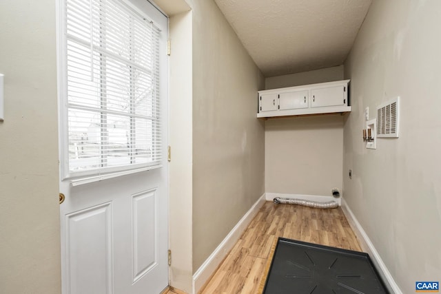 washroom featuring light wood-style flooring, electric dryer hookup, baseboards, and a textured ceiling